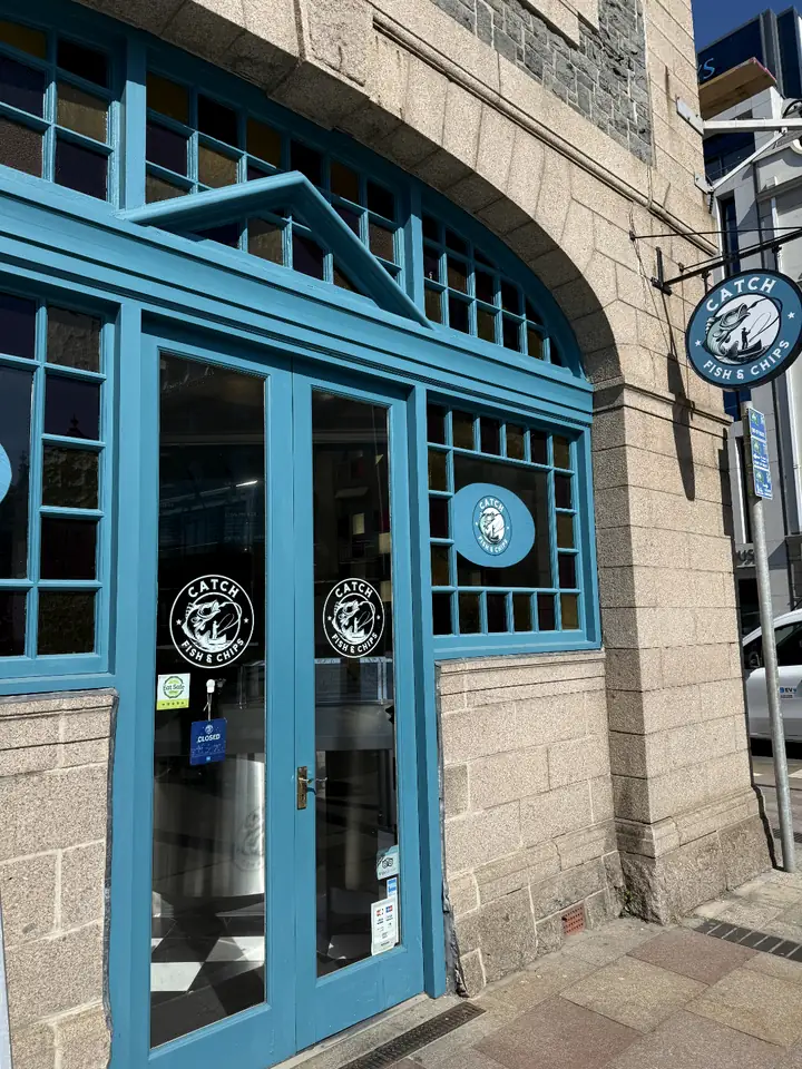 The Catch shopfront with blue window frames and the round fisherman sign, Liberty Wharf